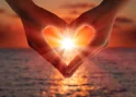 Hands forming a heart shape against a sunset